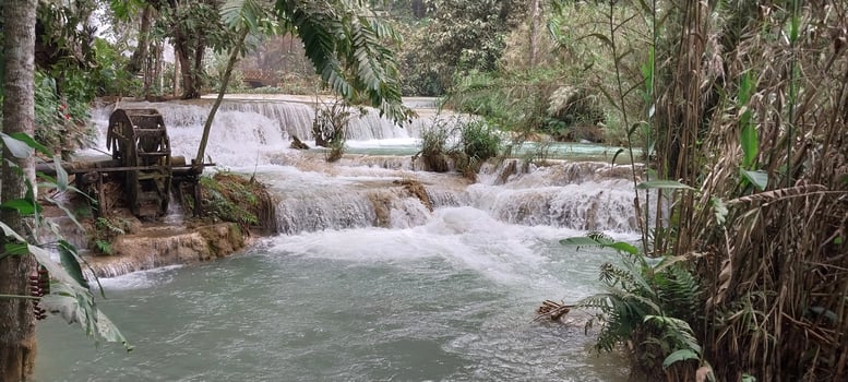 Scenic waterfall surrounded by lush greenery, flowing over rocks into a serene pool, perfect for nature lovers and tranquility seekers. photo