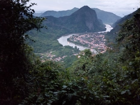 A picturesque village nestled in a lush, green valley with a river winding through, framed by mountains and dense foliage. photo