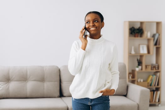 Smiling young black woman talking on the phone in the living room. photo