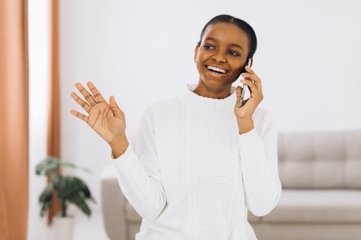 Smiling young black woman talking on the phone in the living room. photo