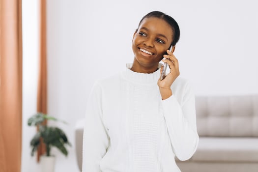Smiling young black woman talking on the phone in the living room. photo