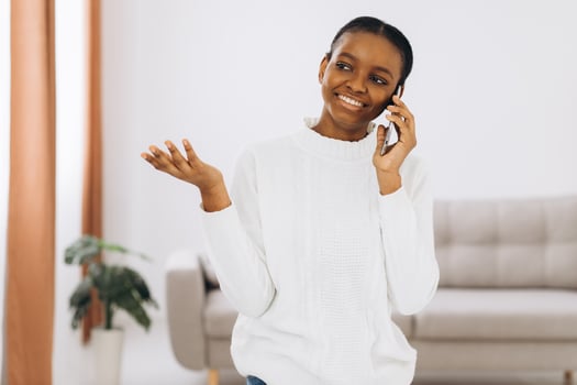 Smiling young black woman talking on the phone in the living room. photo