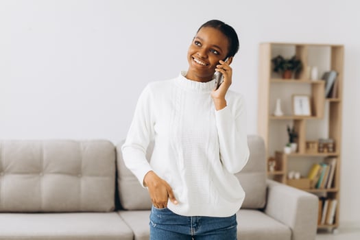 Smiling young black woman talking on the phone in the living room. photo