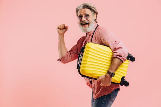 A bearded man holds a yellow suitcase, smiles and prepares for the trip. photo