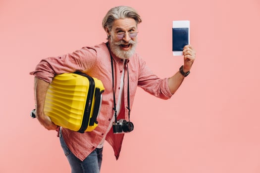 Stylish bearded man with a camera holds a yellow suitcase and a passport with a ticket, smiles and prepares for the trip. photo