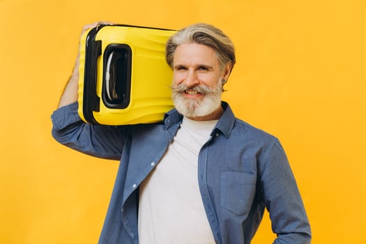 Stylish laughing bearded man holding a yellow suitcase. photo