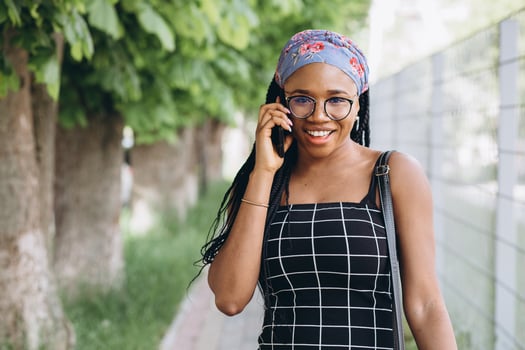 Pretty African American woman in a dress has fun outside and talks by phone photo