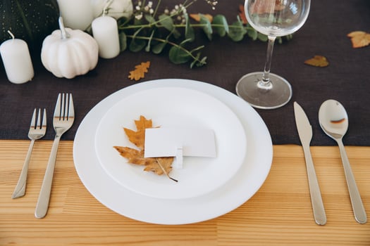 Thanksgiving table setting, tableware and decorations. Blank white postcard on table mockup. photo