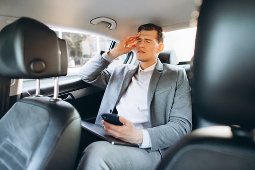 Young businessman tired from work holding hand to his head while sitting in the back seat of the car. photo