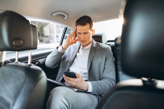 Young businessman tired from work holding hand to his head while sitting in the back seat of the car. photo