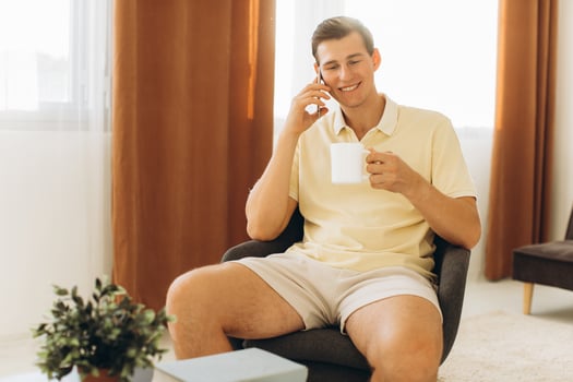 A handsome guy in yellow casual clothes is sitting at home and talking on the phone photo