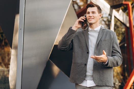 Modern handsome smiling man walking down the street and talking on the phone photo