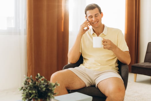 A handsome guy in yellow casual clothes is sitting at home and talking on the phone photo