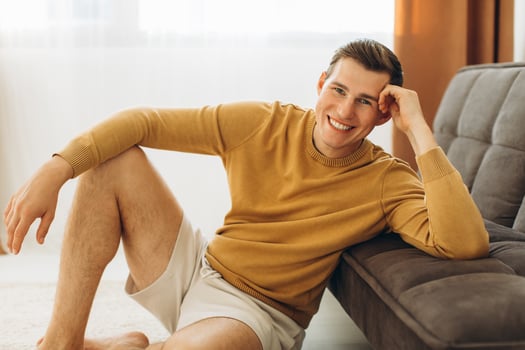 A man in yellow casual clothes is sitting at home and smiling photo