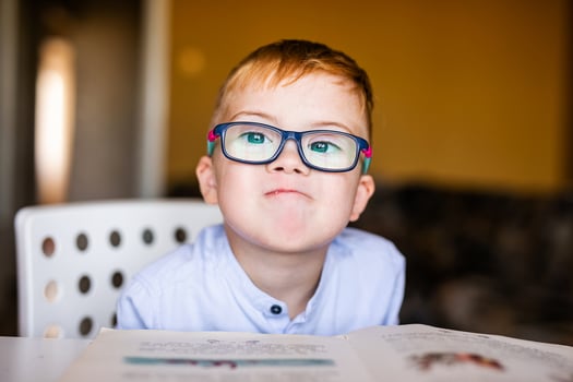 Cute toddler boy with down syndrome with big glasses reading intesting book photo