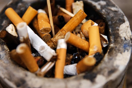 Closeup of an ashtray filled with numerous cigarette butts on a wooden surface, symbolizing smoking habits and litter, smoking harm, urban pollution, unhealthy lifestyle, littering. photo