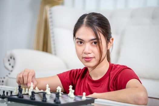 Asian woman playing a game at home, Close up of Woman moving chess, Asian woman plays chess in living room photo