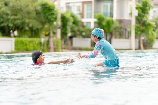 Asian children in swimsuit playing in swimming pool, Asian kids girl playing and having fun in swimming pool photo