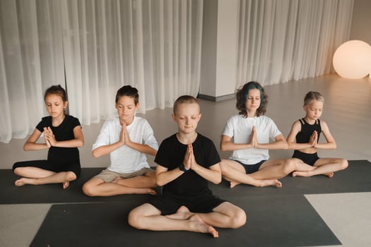Children sit on mats in the lotus position in Yoga classes. Children's yoga photo