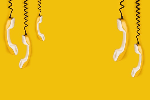 A few yellow old phone handsets dangle on wire. yellow background banner poster copy space photo