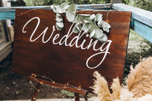 Wooden sign with the inscription wedding on the background of greenery in the restaurant, decor photo