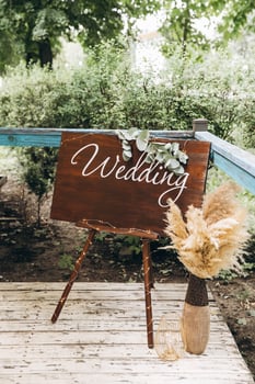 Wooden sign with the inscription wedding on the background of greenery in the restaurant, decor photo