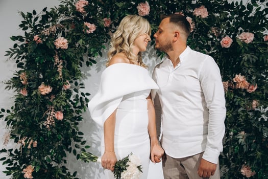 Romantic Wedding Couple Standing in Front of Floral Archway Holding Hands on Special Day photo
