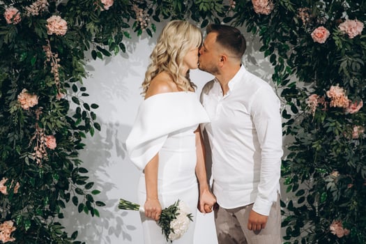 Romantic Wedding Kiss Between Bride and Groom in Floral Decorated Setting photo