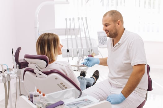 The dentist consults with his female patient sitting in a dental chair photo