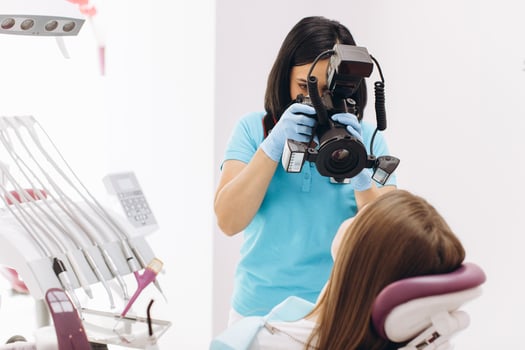 Female dentist photographs her patient's teeth in a dental chair. photo