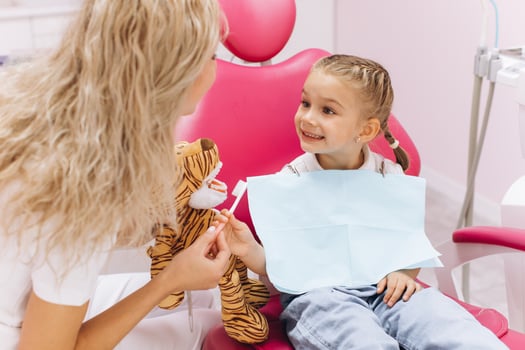 Little girl on a visit to the dentist holding a toy and showing how to brush your teeth in a dental clinic photo