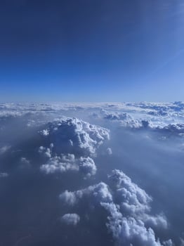 View from airplane window, wing tips, blue sky, white clouds, horizon, jet engine photo