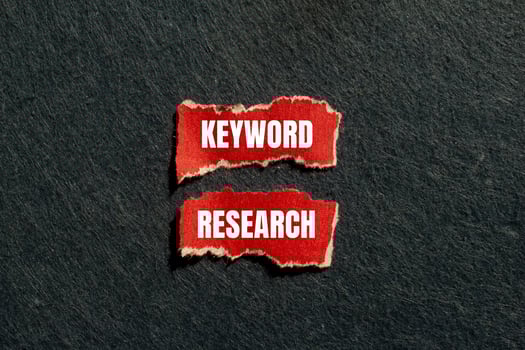Keyword research message written on ripped torn red paper pieces with gray background. Conceptual keyword research symbol. Copy space. photo