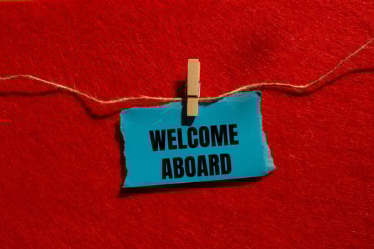 Welcome aboard message written on ripped torn blue paper piece with red background. Conceptual welcome aboard symbol. Copy space. photo