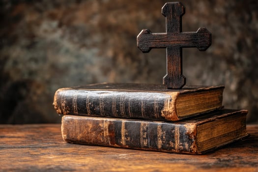 Old books with wooden cross resting on top symbolizing christianity photo