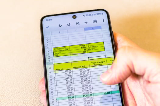 Man scrolling an excel sheet on the phone screen showing bank loan amortization table. Banking photo