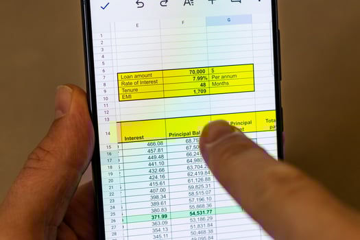 Man scrolling an excel sheet on the phone screen showing bank loan amortization table. Banking photo