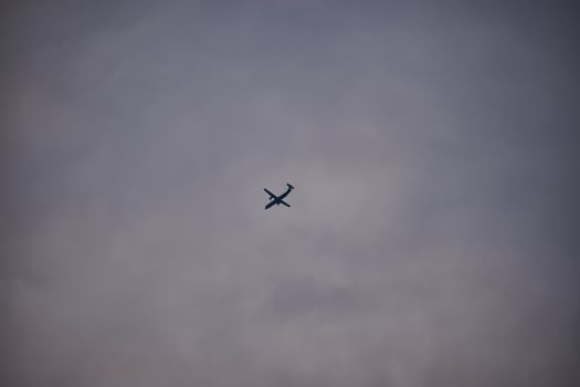 Silhouette of an airplane flying in the middle of a white cloudy sky photo