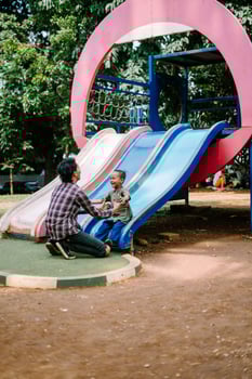 A father and child playing together in a city park playground photo