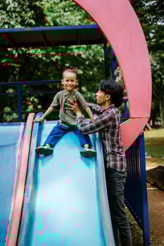 A father and child playing together in a city park playground photo