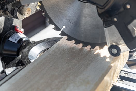 Using a miter saw to cut a piece of wood. Own carpentry workshop. Sawing a wooden board with a miter saw. Safe equipment for the furniture and construction industry. Close-up. photo