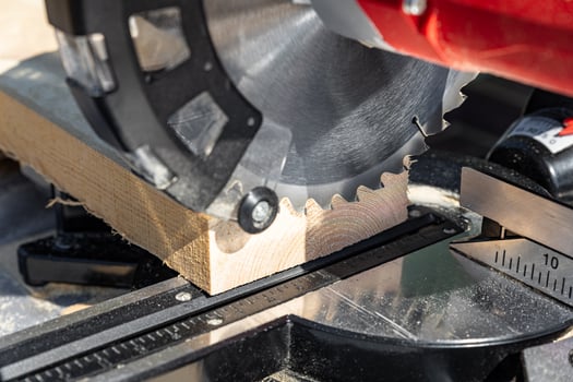 Using a miter saw to cut a piece of wood. Own carpentry workshop. Sawing a wooden board with a miter saw. Safe equipment for the furniture and construction industry. Close-up. photo