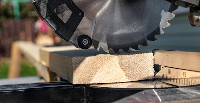 Using a miter saw to cut a piece of wood. Own carpentry workshop. Sawing a wooden board with a miter saw. Safe equipment for the furniture and construction industry. Close-up. photo