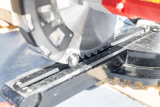 Cuts a wooden beam using a circular saw. Home furniture workshop. Work in his carpentry workshop. Miter saw and planks for building a house. photo