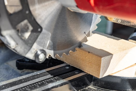 Miter saw tool blade up close for cutting lumber and carpentry. Using a circular saw to cut a wooden board. Blade of a miter saw to cut off the edge of a wooden board, close up. photo
