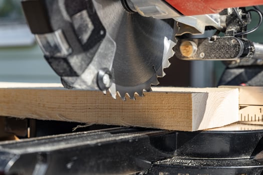 Miter saw tool blade up close for cutting lumber and carpentry. Using a circular saw to cut a wooden board. Blade of a miter saw to cut off the edge of a wooden board, close up. photo