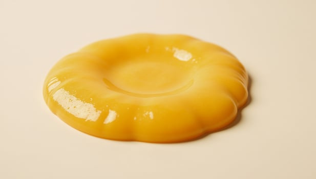 Melted cheese puddle with glossy texture against white backdrop YellowOrange Cheese photo