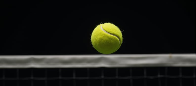 Yellow tennis ball soaring into blackbacked tennis net banner with empty area for text photo