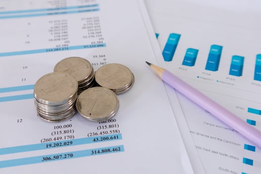 Close up view of stack of coins and pencil on top of financial data paperwork photo