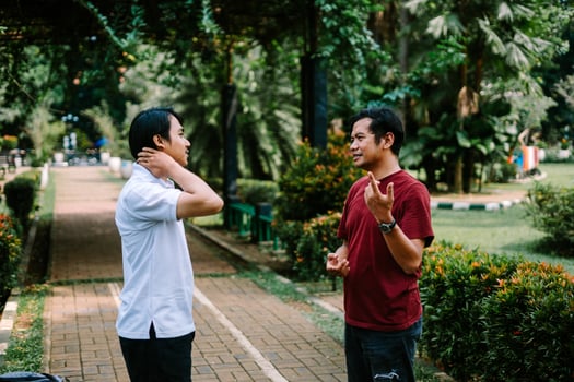 Two Southeast Asian men engaged in a lively conversation at a city square. photo